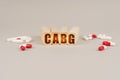 On a gray surface are pills and a red wooden block with the inscription - CABG Royalty Free Stock Photo