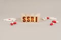 On a gray surface are pills and a red wooden block with the inscription - SSRI