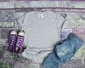 Gray T Shirt mockup flat lay on purple brick background with purple shoes and ripped jeans Royalty Free Stock Photo