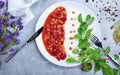 Top view of a white plate with canned beans, fresh salad leaves, bay leaves, seasonings on a light gray background.