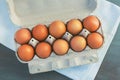 On a gray table is a white towel, on which is a cardboard box from the market with a brown chicken eggs Royalty Free Stock Photo