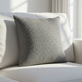 Gray textured pillow on a light-colored sofa, bathed in natural sunlight. The pillow Royalty Free Stock Photo