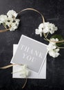 Gray thank you note with white blossoms and a natural ribbon on a black table top Royalty Free Stock Photo