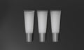 Gray tubes lie on dark background. Translucent tubes with cream