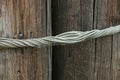 Gray twisted metal wire pulls together two brown wooden pillars