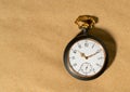 Gray vintage pocket watch with gold hands on a round dial. Old retro clock on a beige background with place for Royalty Free Stock Photo
