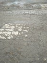 Gray wet asphalt. Damaged asphalt with puddles and stones. Gray routine.