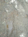 Gray wet asphalt. Damaged asphalt with puddles and stones. Gray routine.