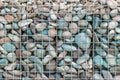 Gray white and blue round stones in metal mesh background. Natural environmental material fencing.