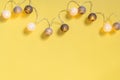 Gray white festive garland on yellow background flat lay top view. Cotton Balls Garland. Round bulbs LED festoon lights electric Royalty Free Stock Photo