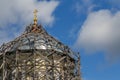 gray wood scaffolds on a dome of russian christian church at day light on blue sky with white clouds