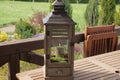 Gray wooden box with glass and a burning candle inside is standing on a brown table