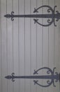 Gray wooden door with ornate black iron wrought brackets