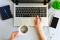 Gray wooden office desk table with laptop computer, smartphone,notebook, pen and cup of coffee. Female hands using a laptop Royalty Free Stock Photo