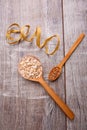 Collecting dry cereals. On a wooden background in spoons oatmeal and buckwheat. Royalty Free Stock Photo