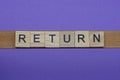 Gray word return in small square wooden letters