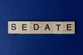 Gray word sedate in small square wooden letters with black font
