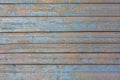 Gray yellow old fence wall of wooden planks with blue peeling paint and cracks. horizontal lines. rough surface texture Royalty Free Stock Photo