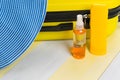 On a gray-yellow surface, a set for recreation, a hat , a suitcase for traveling and sunscreens Royalty Free Stock Photo