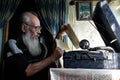 Graybeard old man in glasses sitting near an antique gramophone