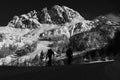 Grayscale beautiful view of skiers on a snowy mountain during sunrise