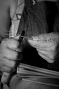 Grayscale closeup shot of a female craftsperson sharpening a thin piece of wood with a knife