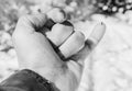 Grayscale closeup shot of a man's hand with a thorn on his pinky finger