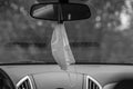 Grayscale closeup shot of a medical mask hanging on a car window