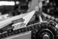 Grayscale closeup shot of a motor chain with timbers on it.