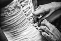 Grayscale closeup shot of a woman making a bow-knot on the back of the bride& x27;s wedding dress. Royalty Free Stock Photo