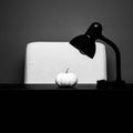 Grayscale closeup of a table lamp with a small pumpkin.