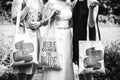 Grayscale closeup of three females holding bridesmaid clothesbag