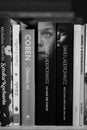 Grayscale closeup view of a row of books standing on a wooden shelf including Coben.