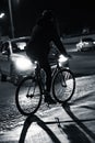 Grayscale of a cyclist riding a bicycle in the street in the evening, blurred background