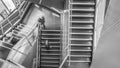 Grayscale high angle shot of people walking down the stairs in a building