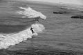 Grayscale high angle shot of a surfer catching waves on the sea