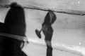 Grayscale hot of a person shadow holding a wine glass over a wooden surface