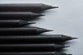 Grayscale image of a group of sharp pencils on a table with an indistinct shadow, close-up