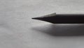 Grayscale image of a sharp pencil on a table with an indistinct shadow, close-up