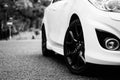 Grayscale low angle shot of a white Mazda driving in the street of Wolverhampton city in the UK