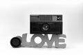 Grayscale of an old instamatic camera and its lens on a decoration reading love