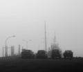 Grayscale of parked cars on the port with a boat on the foggy background