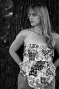 Grayscale photo of a blonde girl leaning against a tree Royalty Free Stock Photo