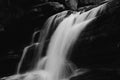 Grayscale photography of a strong running waterfall in a forest