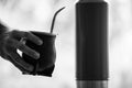 Grayscale selective focus shot of a hand holding a calabash mate cup with straw