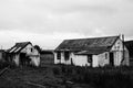 Grayscale shot of abandoned house and barn in a field