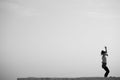 Grayscale shot of an adult female doing yoga under the open sky