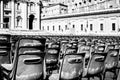 Grayscale shot of black plastic chairs in a square in Rome