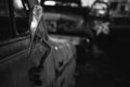 Grayscale shot of the broken mirror of an abandoned car with a blurry background