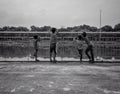 Grayscale shot of children standing by the railings of a sidewalk overlooking a river